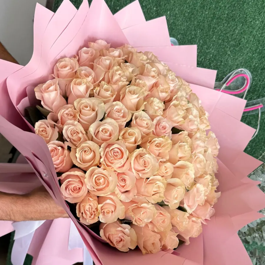 Large bouquet of pale peach roses wrapped in pink paper
